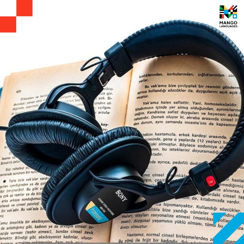 An open book with a pair of headphones laid on top of it.