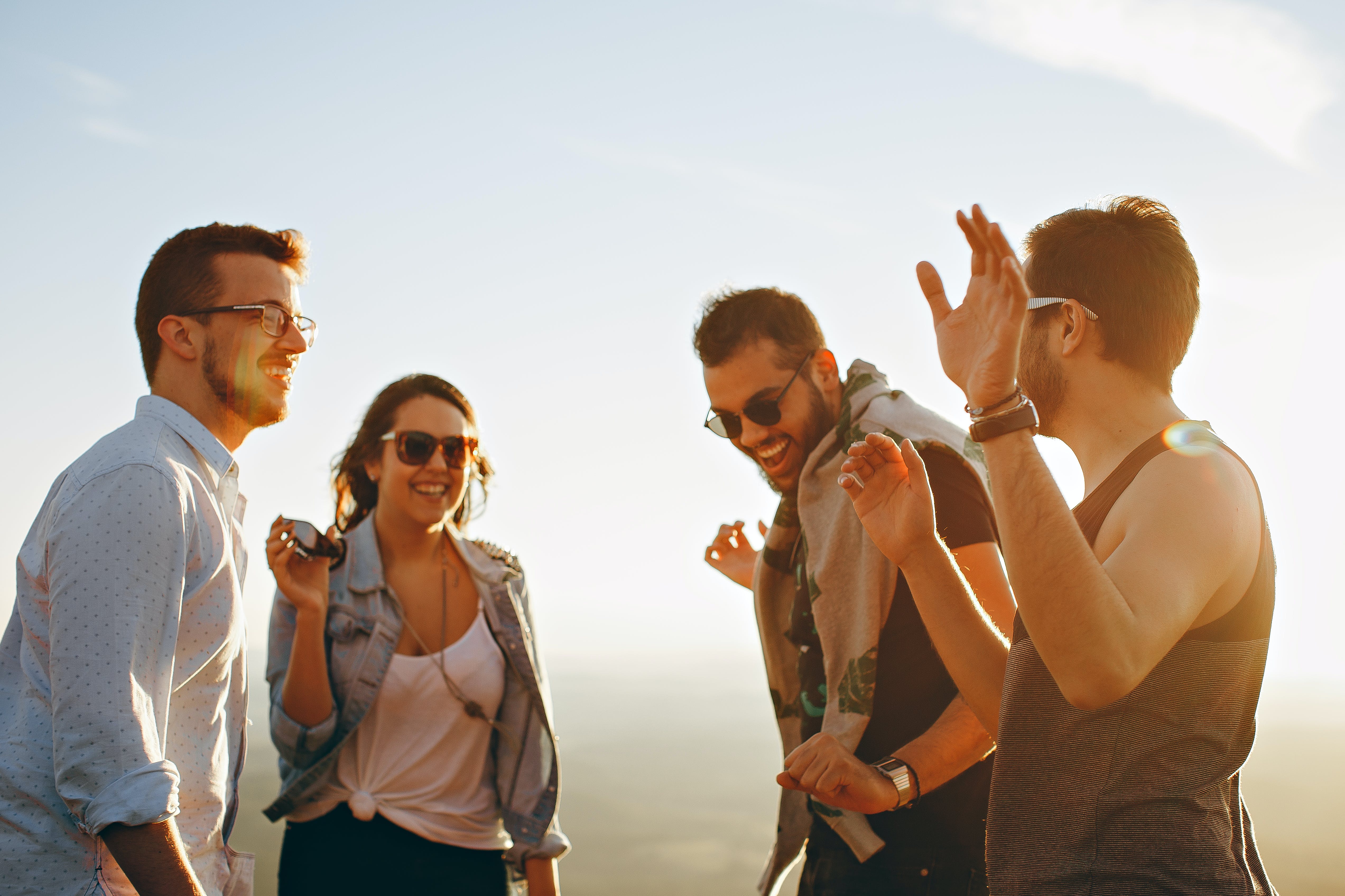 Four friends smiling and having a conversation outside in the sunset