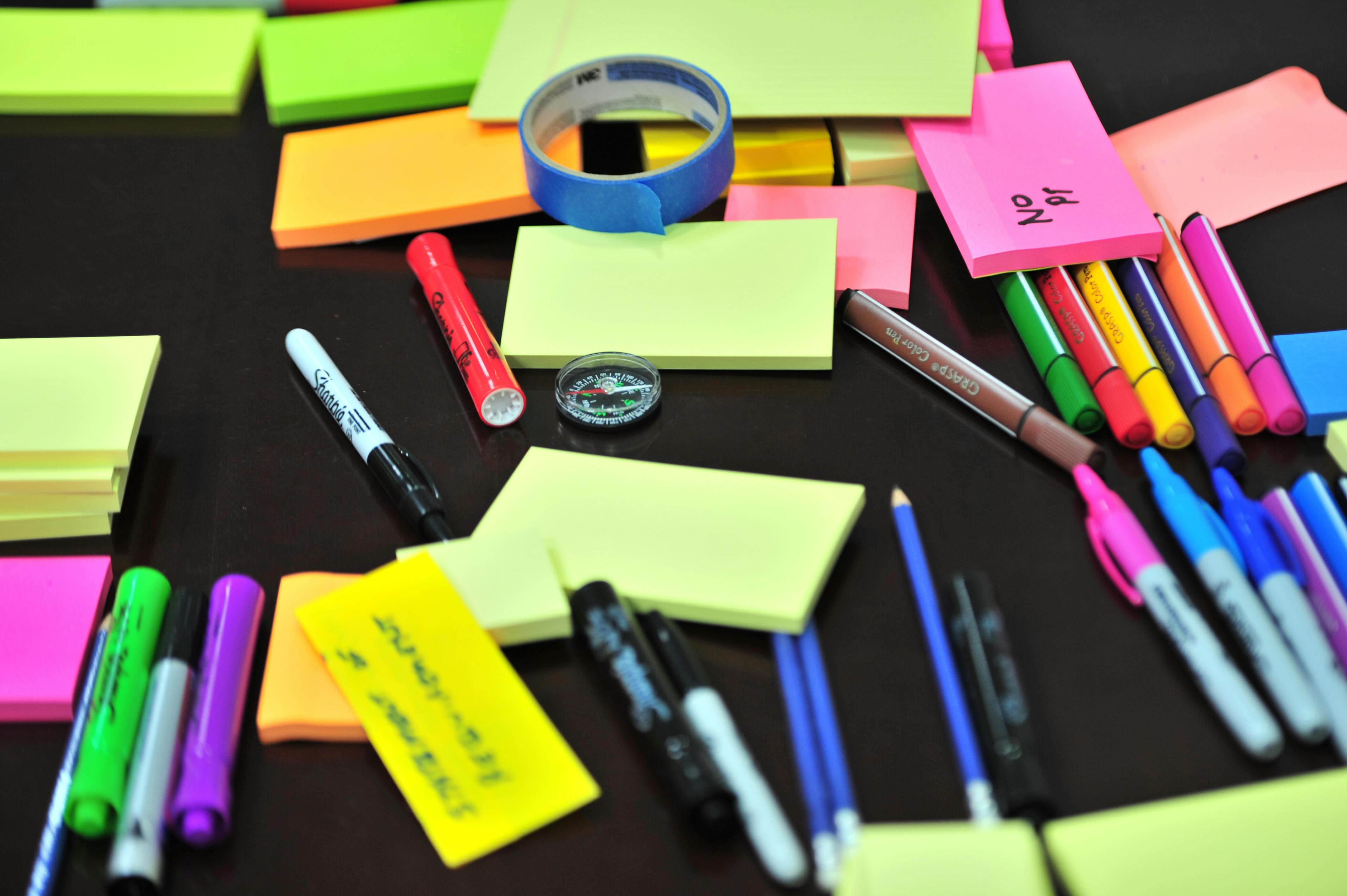 A desk covered with markers and post-it notes