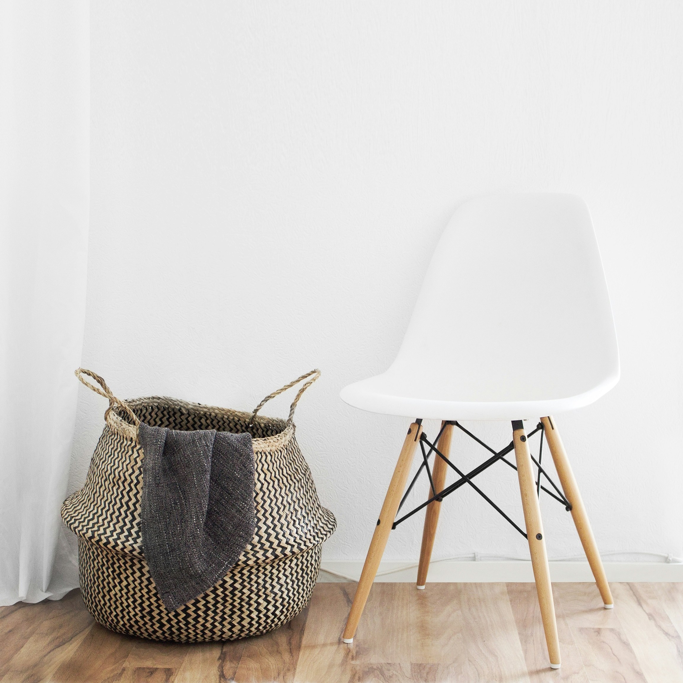 A white chair sits beside a large basket