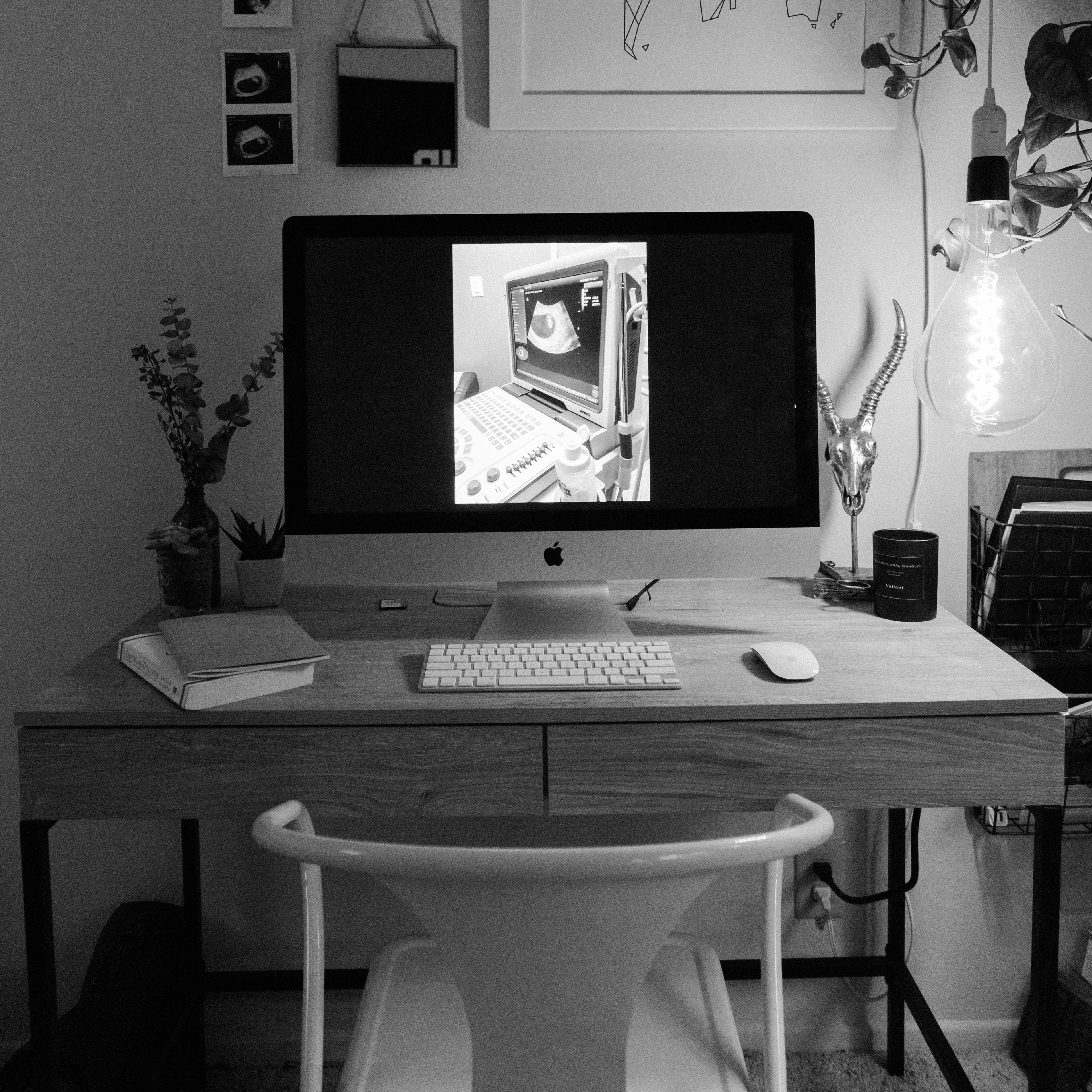 A chair sitting in front of a fashionable desk with a large Apple monitor