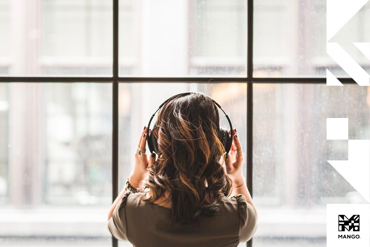 Young woman wearing headphone, staring outside of a window