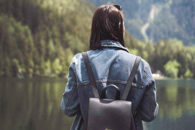 A girl wearing a black backpack outside on a lake