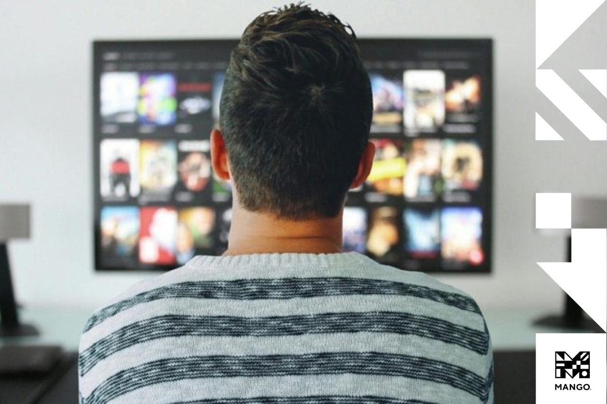 Man sitting down in a living room selecting a film to watch on his TV