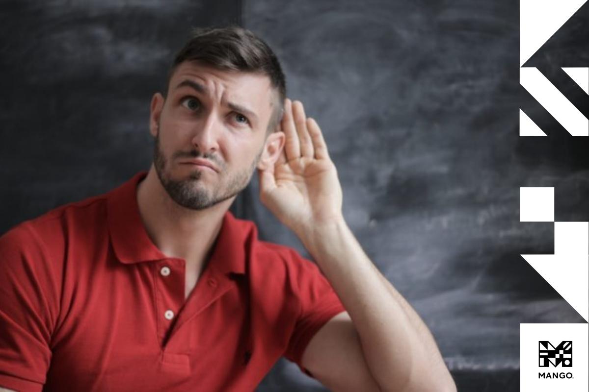 Young man wearing a red shirt cupping his left ear to hear better