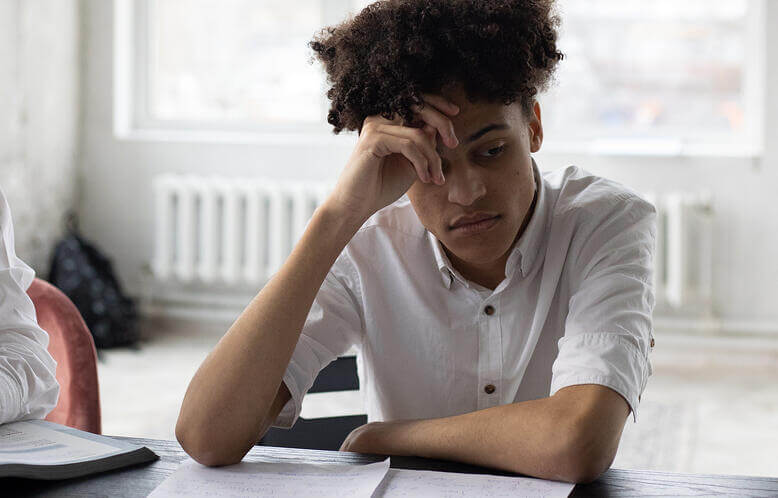 A young man deep in though while studying