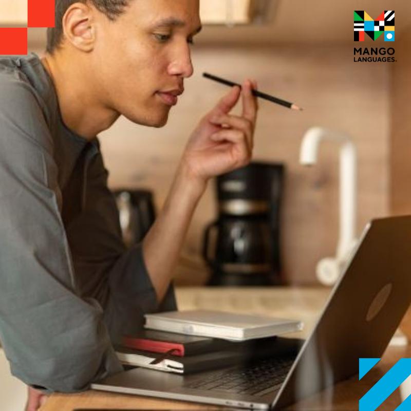 A young man working on his laptop while taking notes