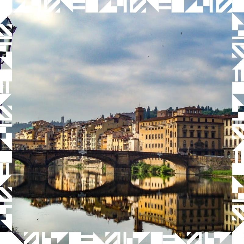 City shot of an Italian city with a bridge over a river surrounded by buildings