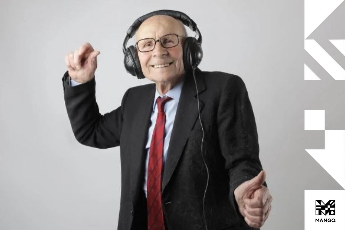 An older gentleman dressed in a suite dancing while listening to music