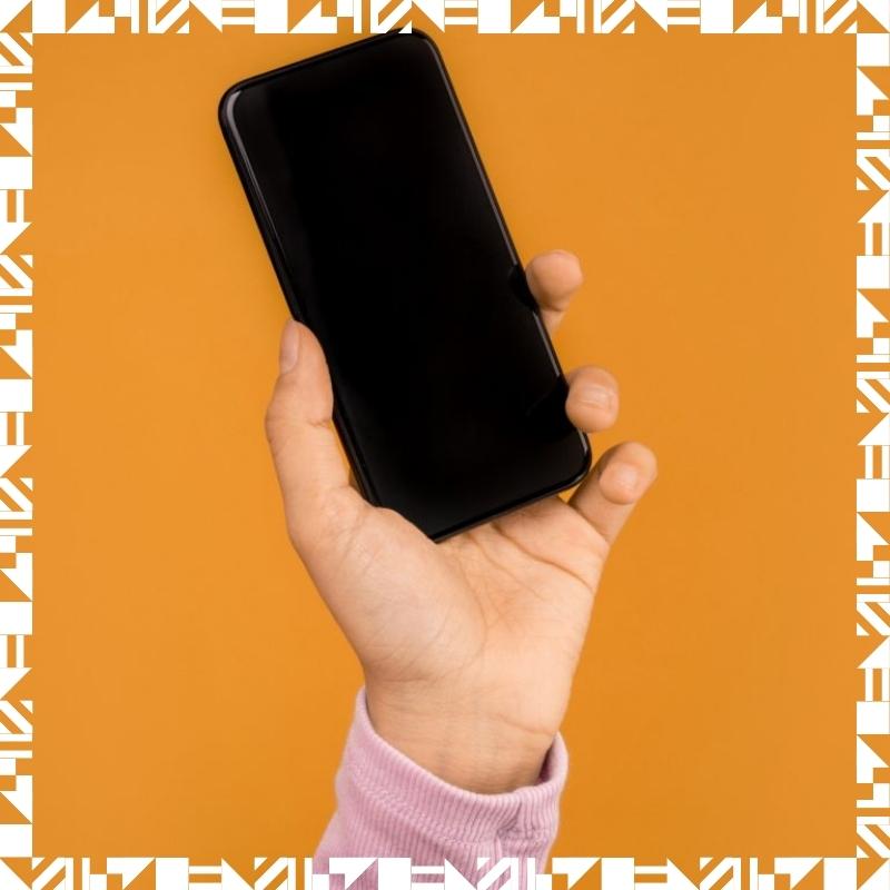 A person holding a smartphone in front of an orange background