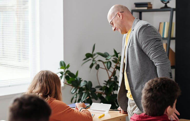 A teacher holding a class and assisting a student